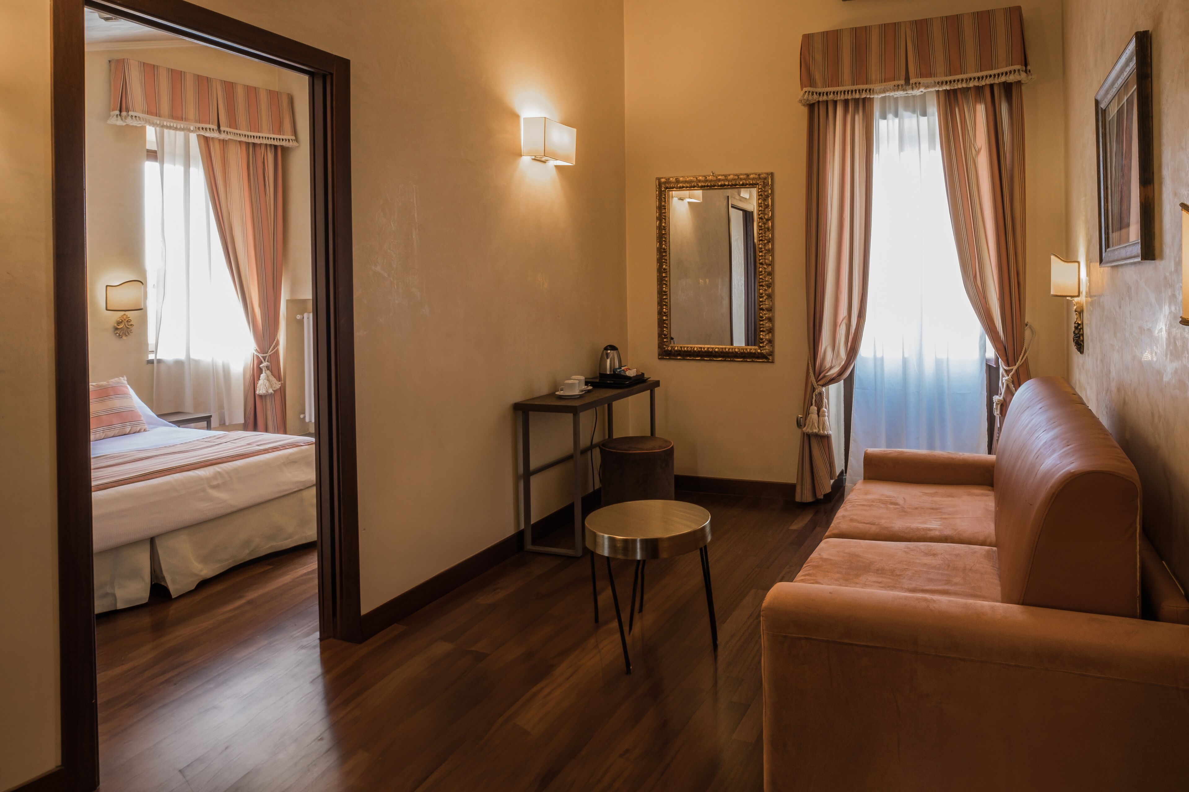 Ein Hotelzimmer mit Bett, Schlafsofa, kleinem Tisch, Spiegel und Nachttisch.