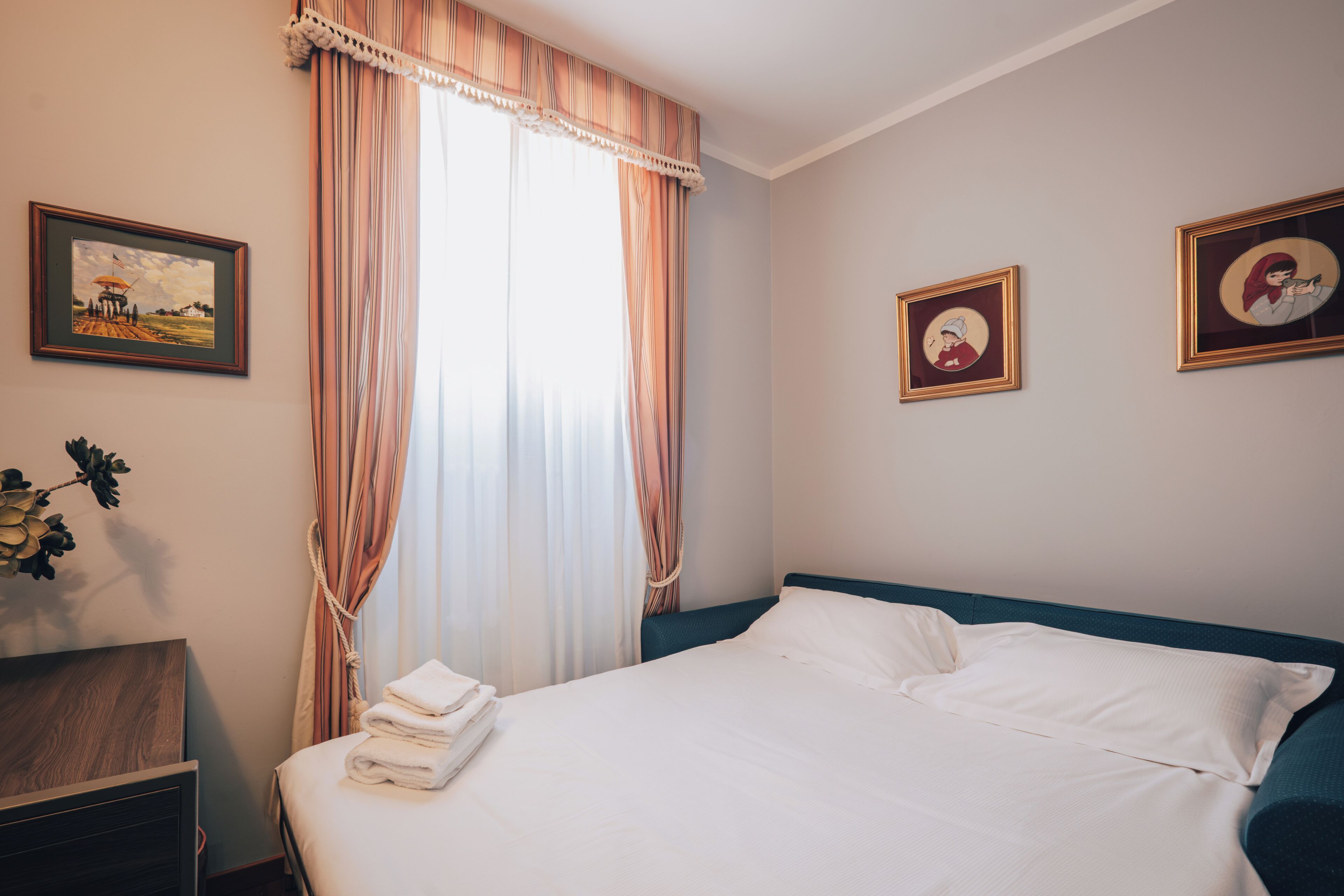 A neatly made bed with white linens, a wooden nightstand, and a framed picture on the wall.