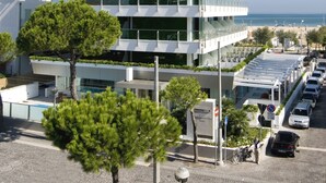 Ein mehrstöckiges Gebäude mit einem 'CLUBHOUSE'-Schild, mit Balkonen, einer Dachterrasse und Blick auf den Strand.