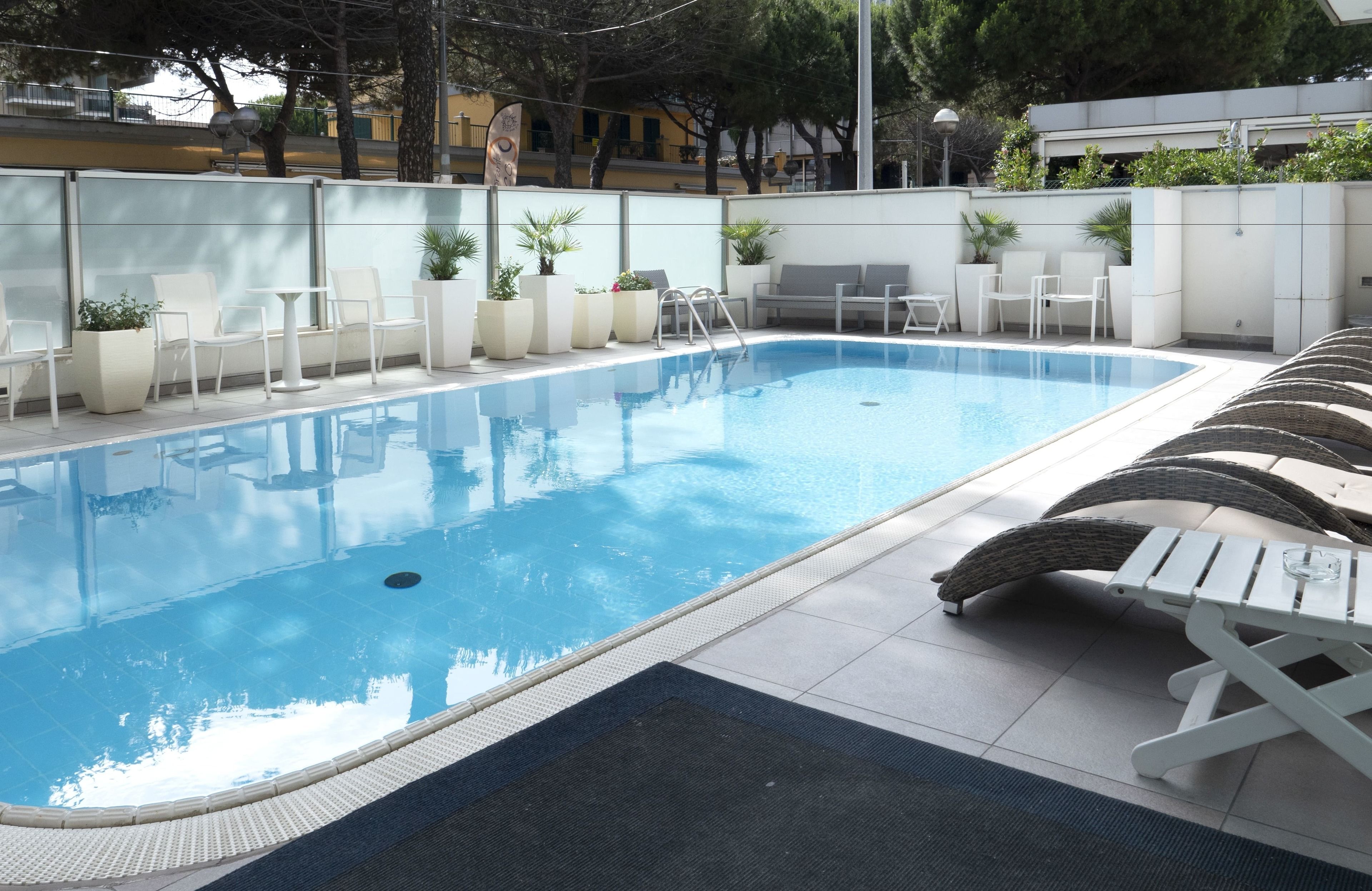 A swimming pool with lounge chairs and potted plants.