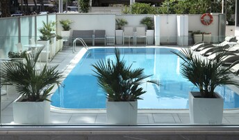 A swimming pool with lounge chairs and potted plants.