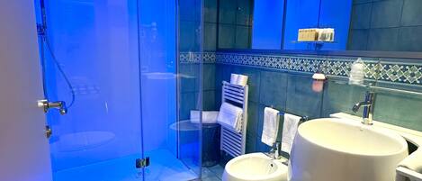 Une salle de bain moderne dotée d’une douche à parois de verre, d’un bidet et d’un grand lavabo.