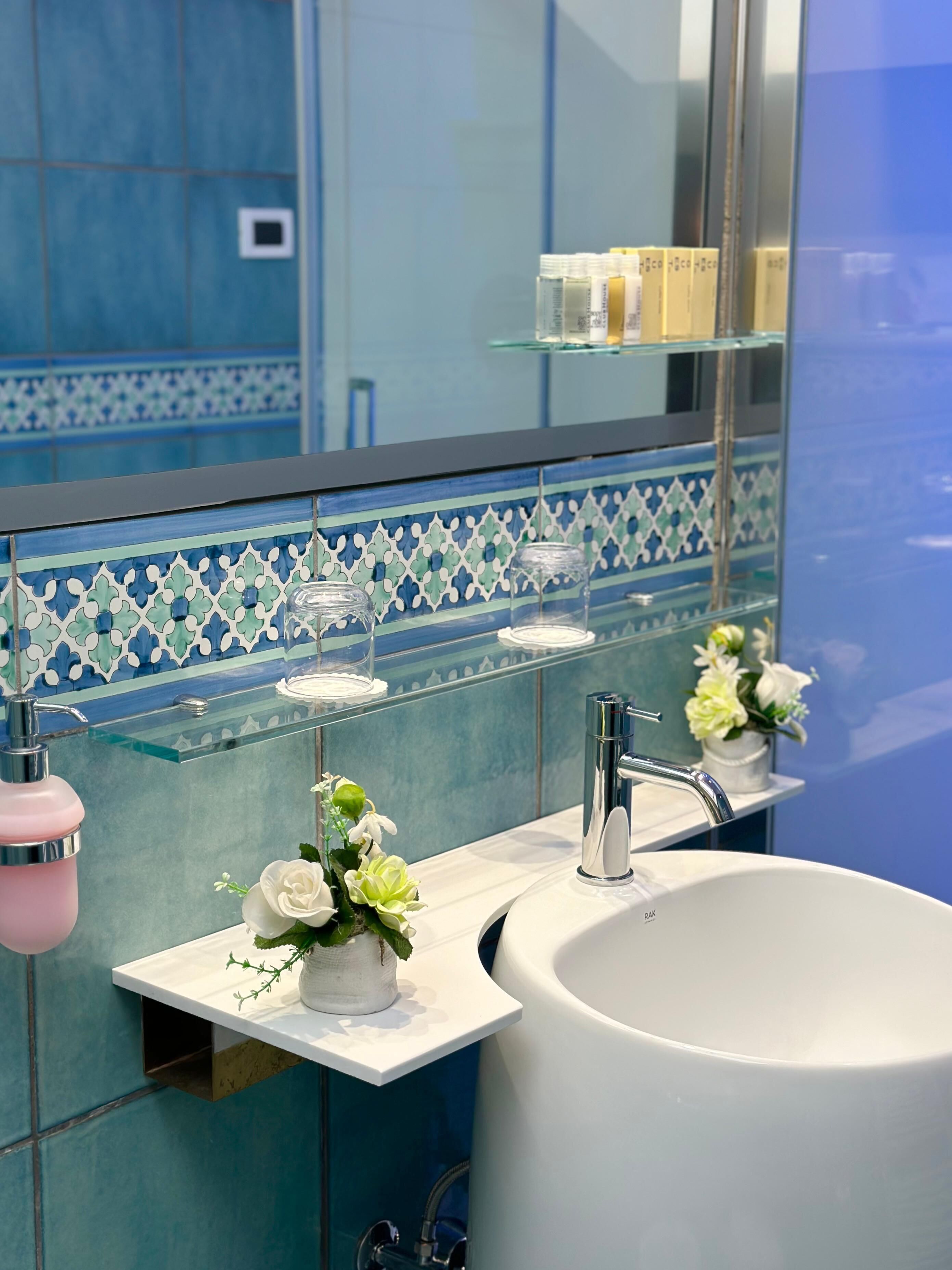 A bathroom with a white sink, a mirror, and a decorative tile backsplash.