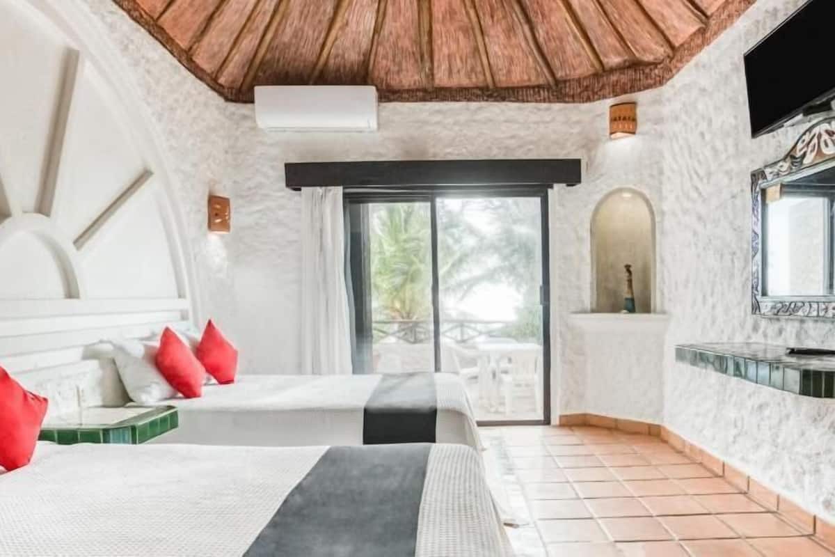 Een hotelkamer met twee bedden, een televisie, een groot raam en uitzicht op het omliggende landschap.