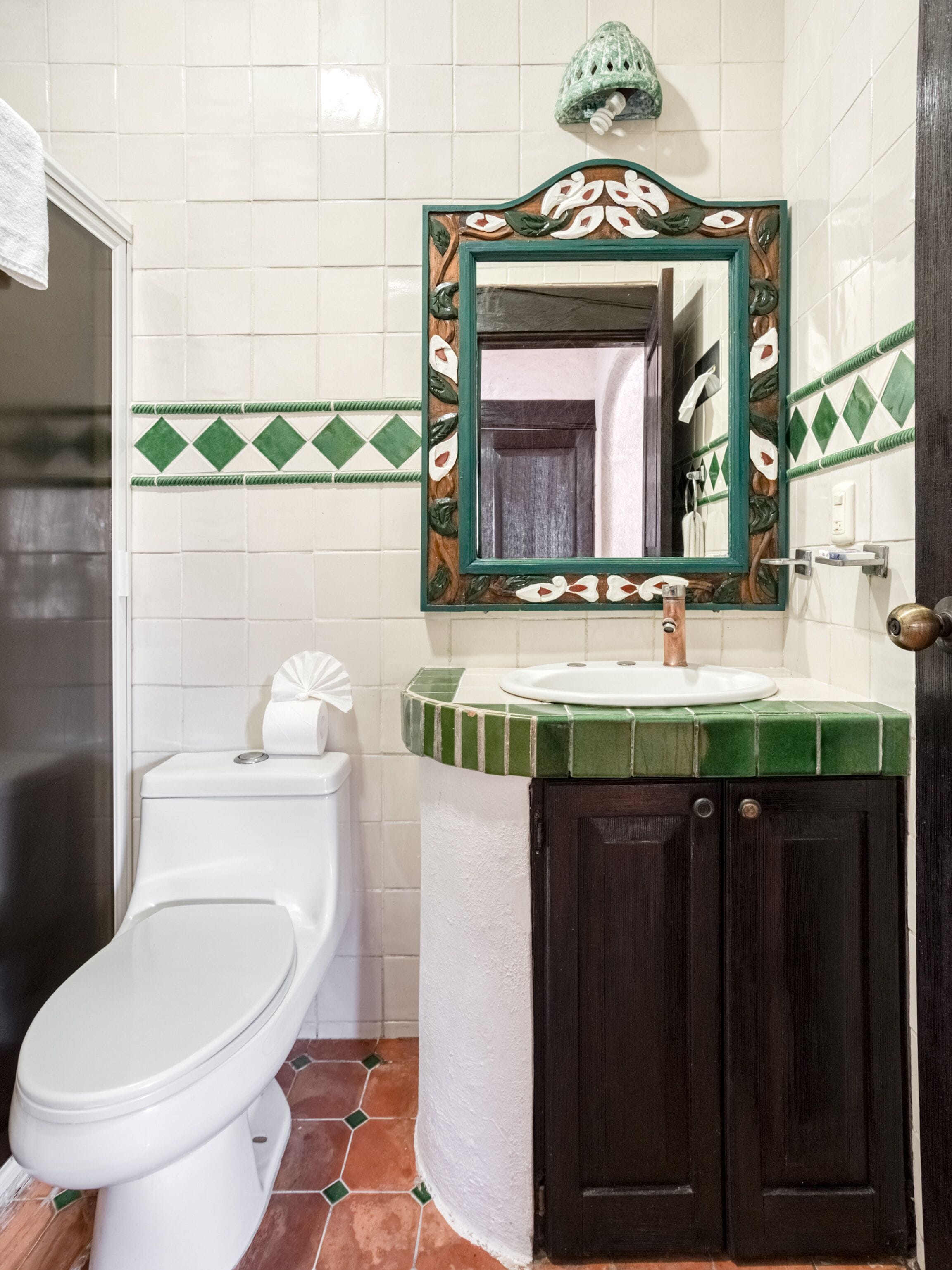 Casa de banho com sanita, lavatório e espelho.
