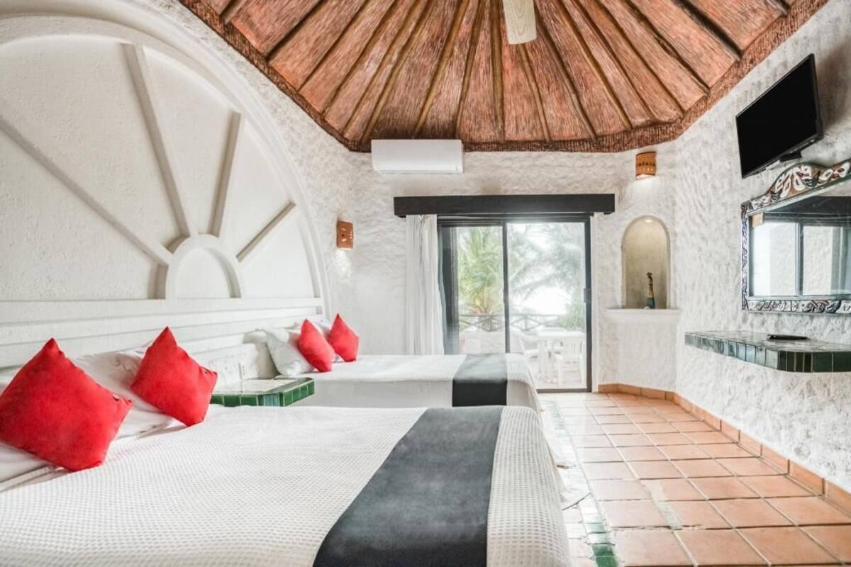Een hotelkamer met twee bedden, een groot raam, een televisie en een betegelde vloer.