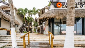 A wooden staircase leading to a building with a thatched roof and palm trees. - Capital O Mimi Del Mar, Playa del Carmen (Playa del Carmen)
