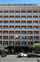 Un hotel a più piani con balconi, un negozio con la scritta "ORIENTE" e bandiere.