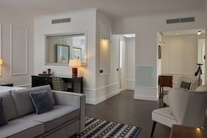A modern hotel room with a sofa, a desk, a chair, and a large mirror. - Grand Hotel Oriente (Naples)