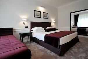 Una camera d'albergo con un letto grande, due comodini, una scrivania e uno specchio.