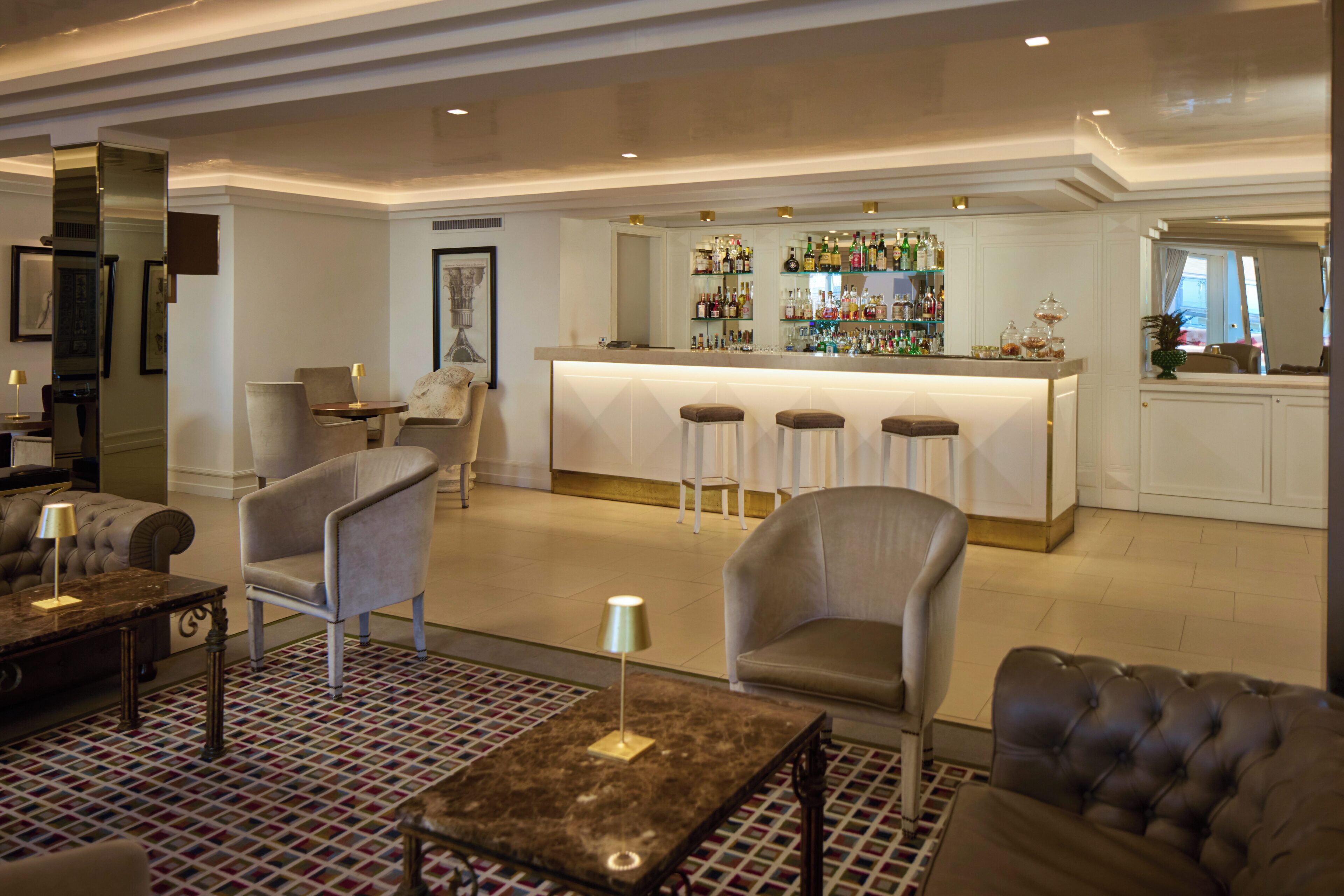 A bar area with stools, a counter, and a variety of bottles.