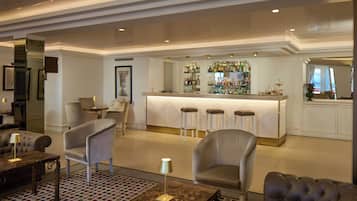 A bar area with stools, a counter, and a variety of bottles.