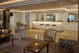 Een bar met krukken, een toonbank en diverse flessen.