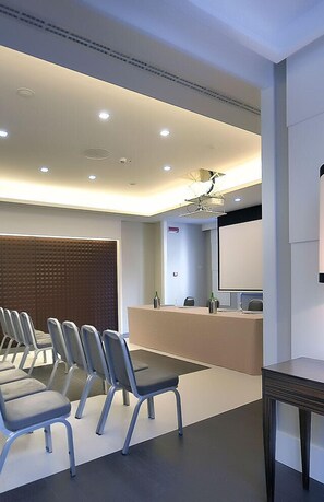 A modern conference room with a long table, several chairs, a podium, and a large screen. - Grand Hotel Oriente (Naples)