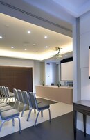 Une salle de conférence moderne équipée d’une longue table, de plusieurs chaises, d’un pupitre et d’un grand écran.