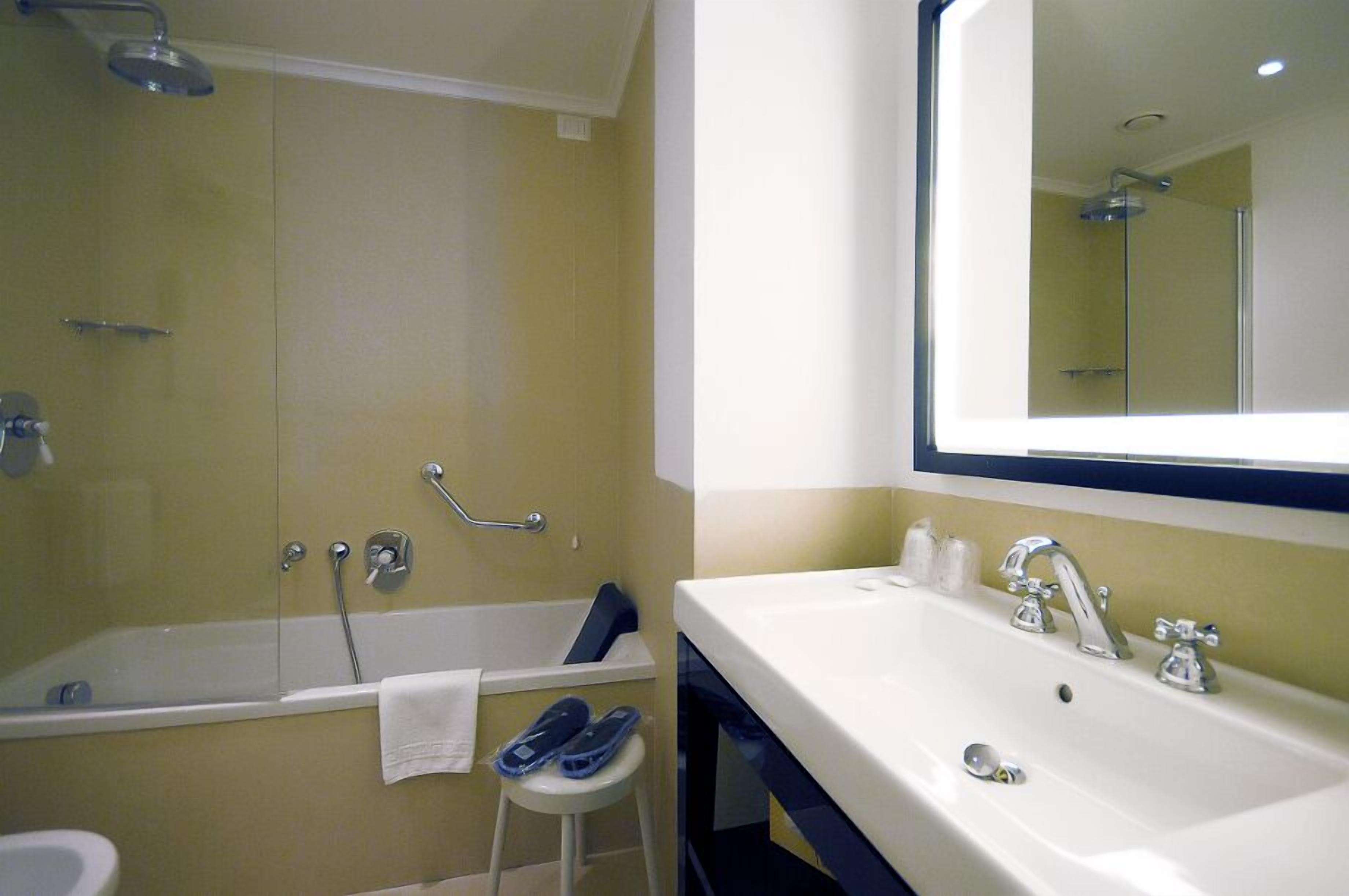 A bathroom with a bathtub, a shower, and a sink with a large mirror.