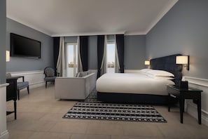 Habitación de hotel con cama, sofá, televisión y vistas a la ciudad.