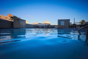 A swimming pool with a waterfall feature, lounge chairs, and a lifebuoy on the wall. - Coral by the Sea Hotel (Carolina)