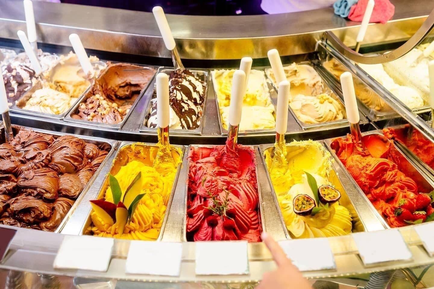 Variedad de sabores de helado en un congelador, cada uno con un asa blanca.