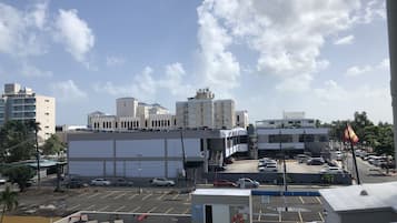 A hotel with a rooftop pool, a parking lot, and a view of surrounding buildings.
