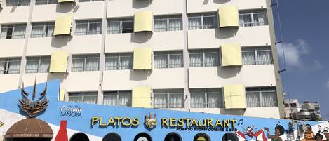 A building with multiple air conditioning units, a mural with the name 'Platos Restaurant' and 'Puerto Rican Cuisine & Bar', and a Coca-Cola logo.