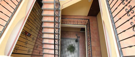 A spiral staircase with a metal railing, leading to a door with a small potted plant on the ground.