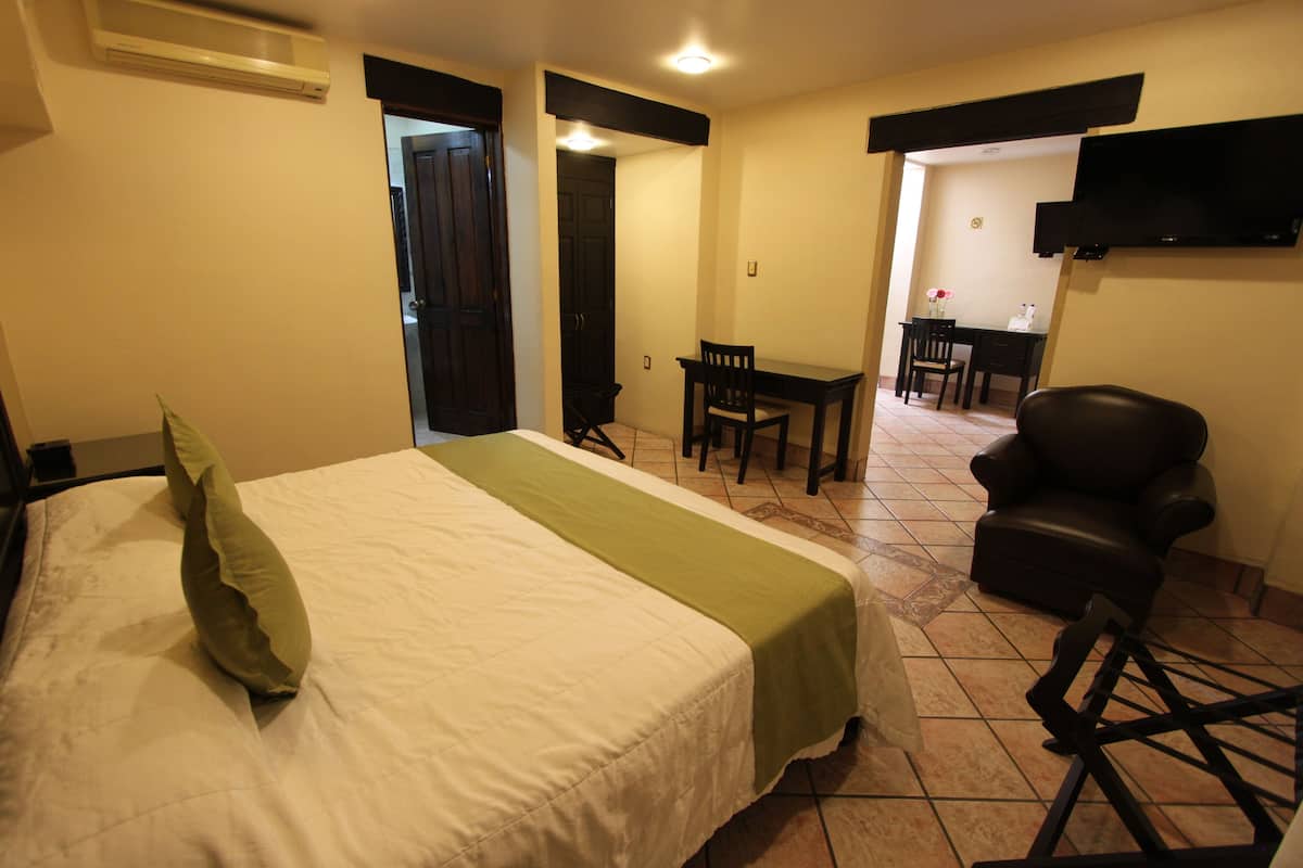 Una habitación de hotel con cama, escritorio, silla y televisor.