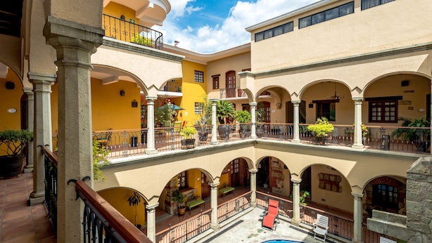 Une cour intérieure à plusieurs niveaux, dotée d’espaces de détente en plein air, d’une piscine et présentant un mélange de styles architecturaux, notamment des arches et des colonnes.