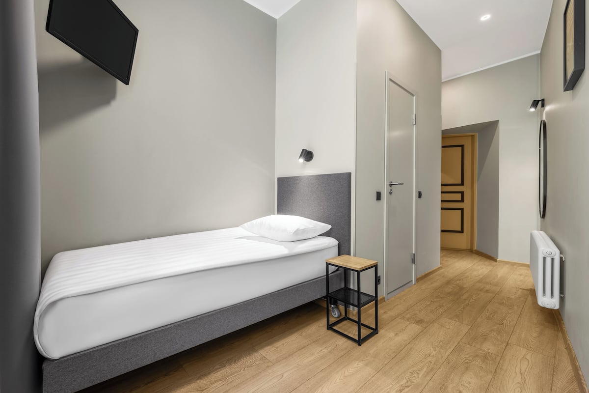Ein kleines, ordentlich eingerichtetes Schlafzimmer mit einem Einzelbett, einem Nachttisch und einem Kleiderschrank.