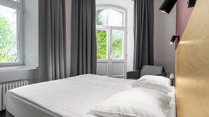 Une chambre d’hôtel avec un grand lit, une chaise, un bureau et une fenêtre avec des rideaux.