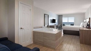 Una habitación de hotel moderna con una bañera grande, una cama, un escritorio y un balcón con vistas.