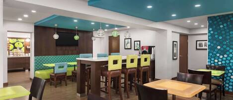 A restaurant with booths and tables, wooden floors, and a blue ceiling.