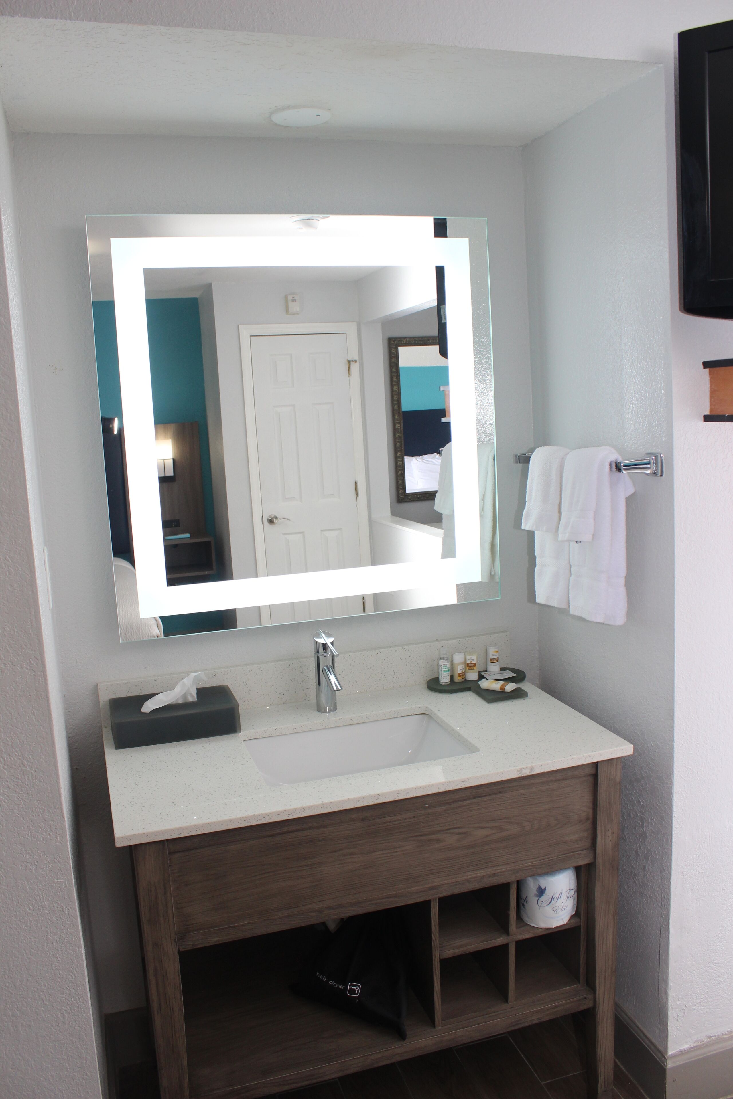 A bathroom with a large mirror, a white sink, and a towel rack.