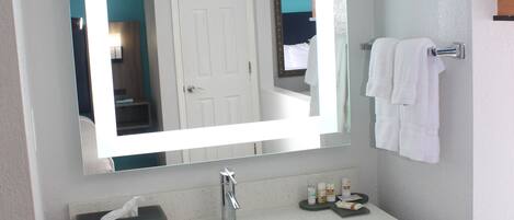 A bathroom with a large mirror, a white sink, and a towel rack.