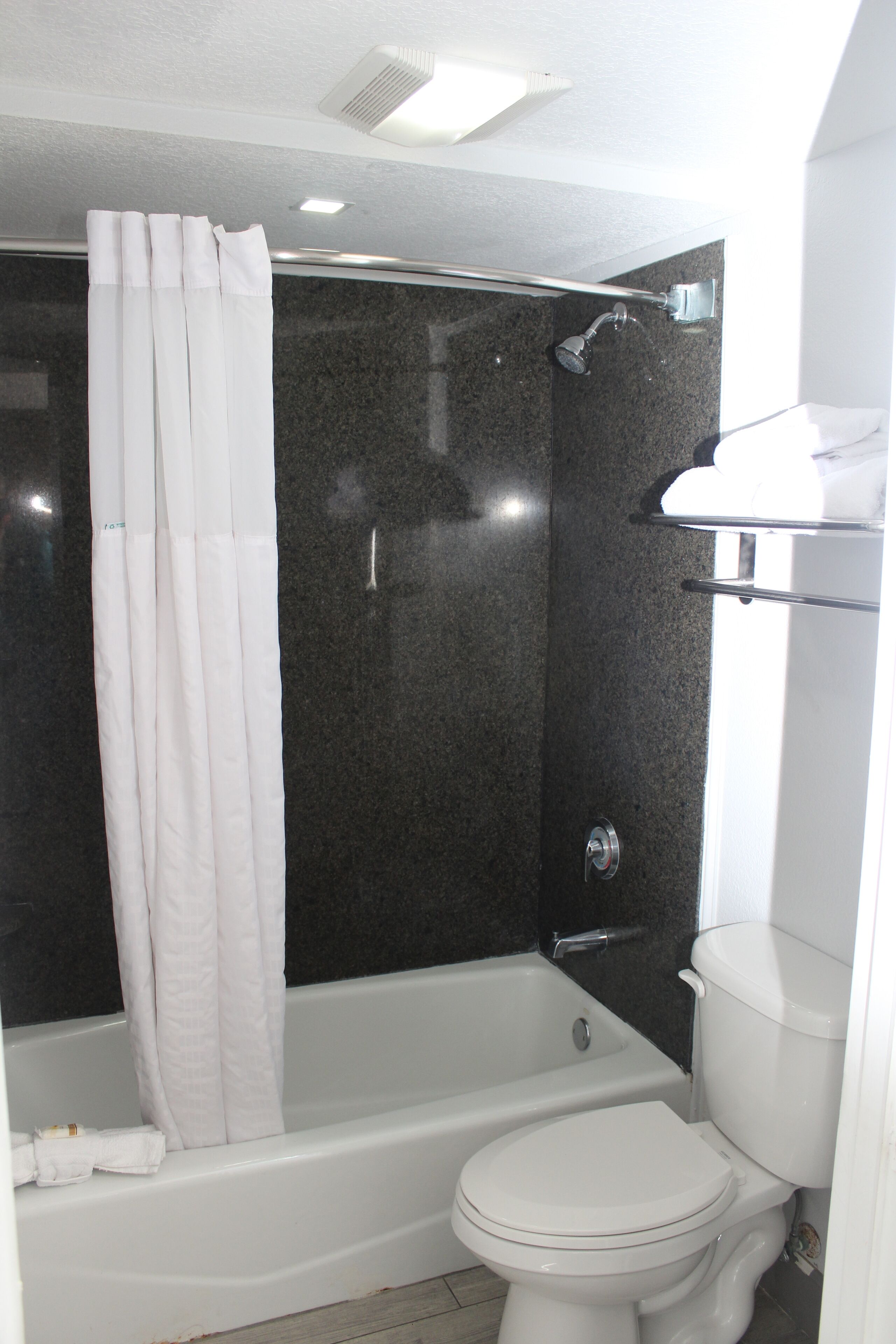 Un baño con bañera, inodoro y cortina de ducha.