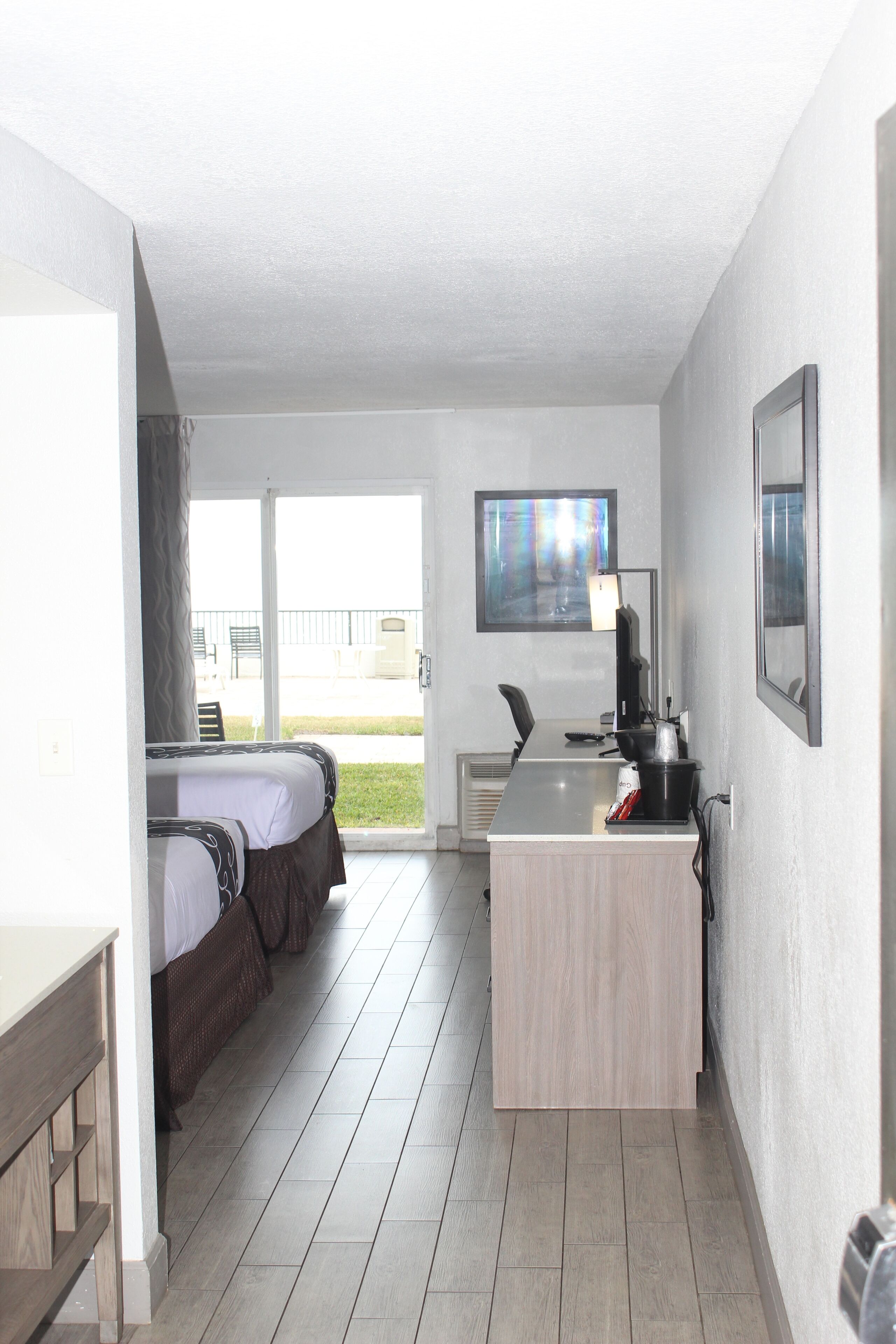 A hotel room with a bed, a desk, a chair, a TV, and a window.