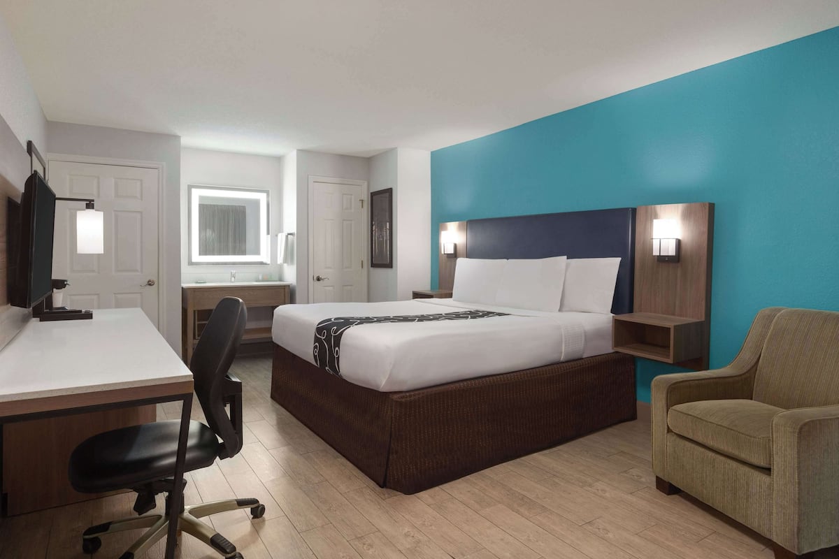 Ein Hotelzimmer mit Bett, Schreibtisch, Stuhl und einer blauen Akzentwand.