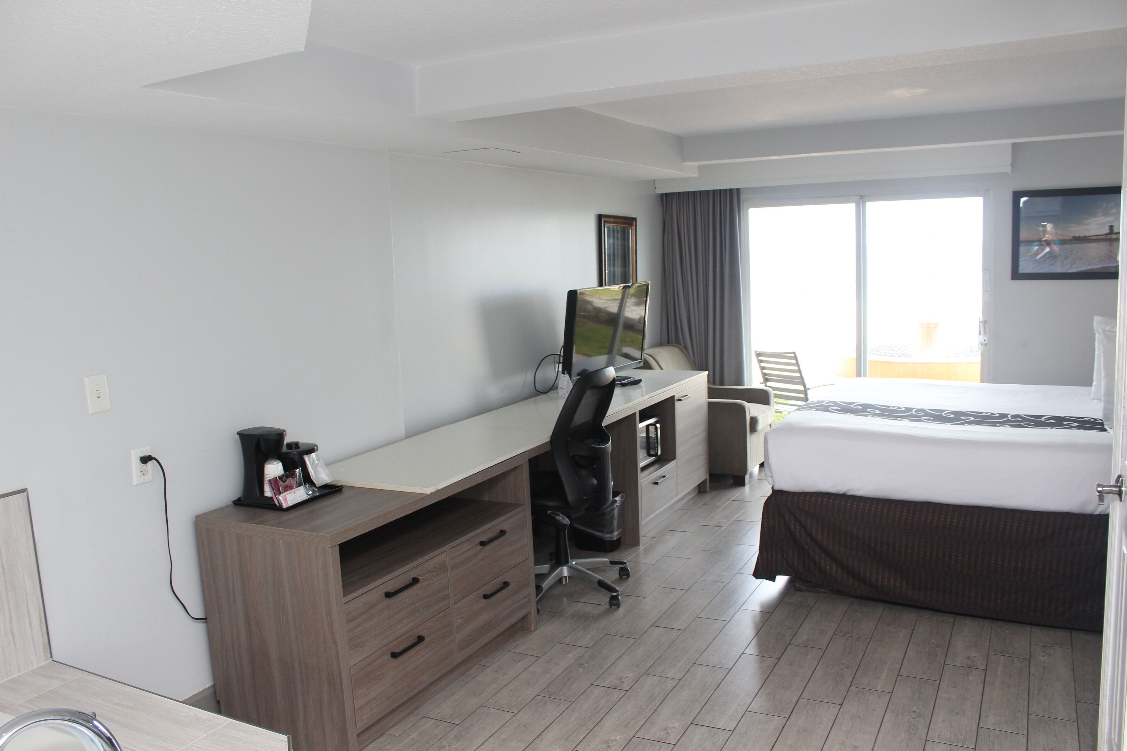 Ein Hotelzimmer mit Bett, Schreibtisch, Stuhl und einem Fenster mit Vorhängen.