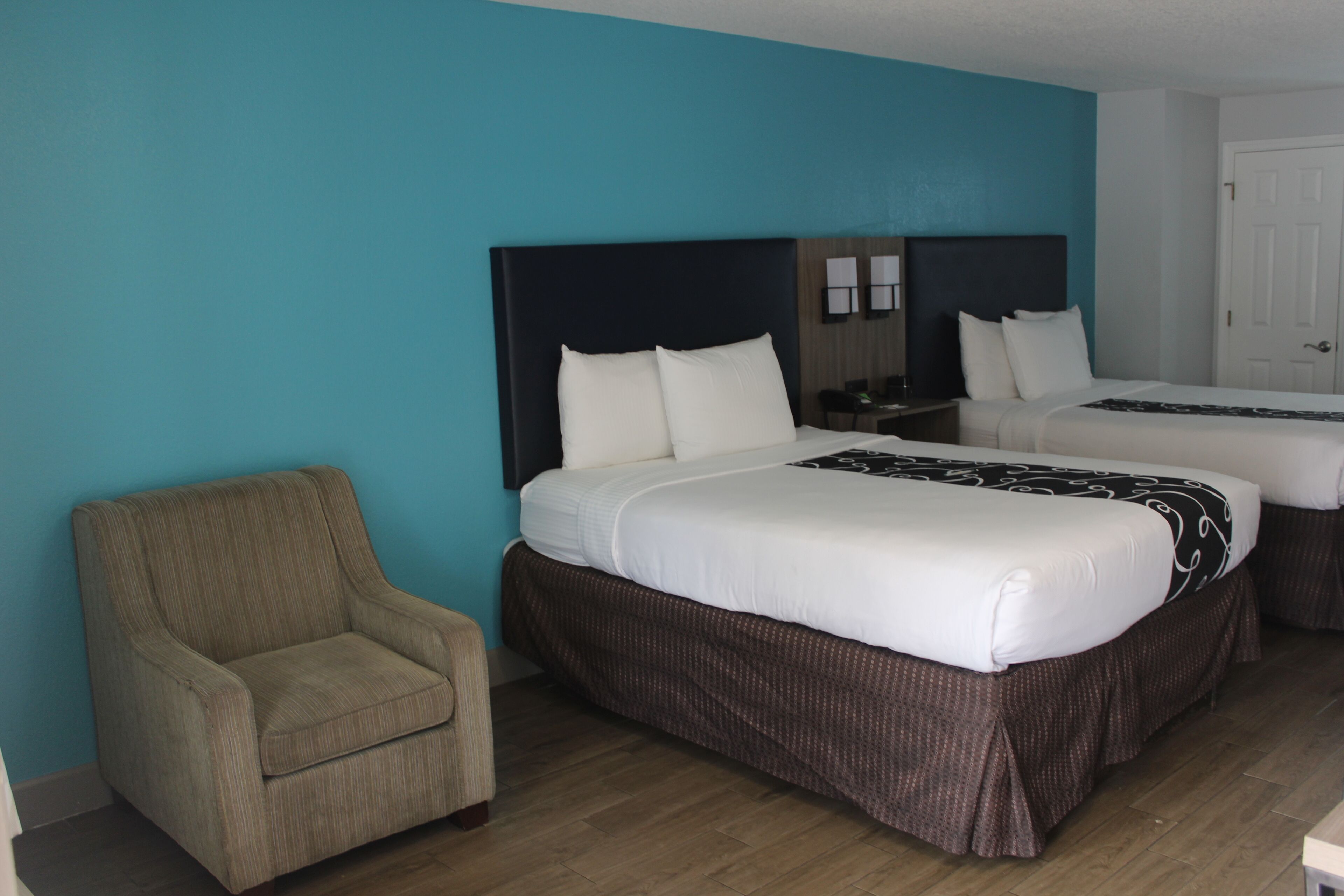 Een hotelkamer met twee bedden, een stoel en een nachtkastje.