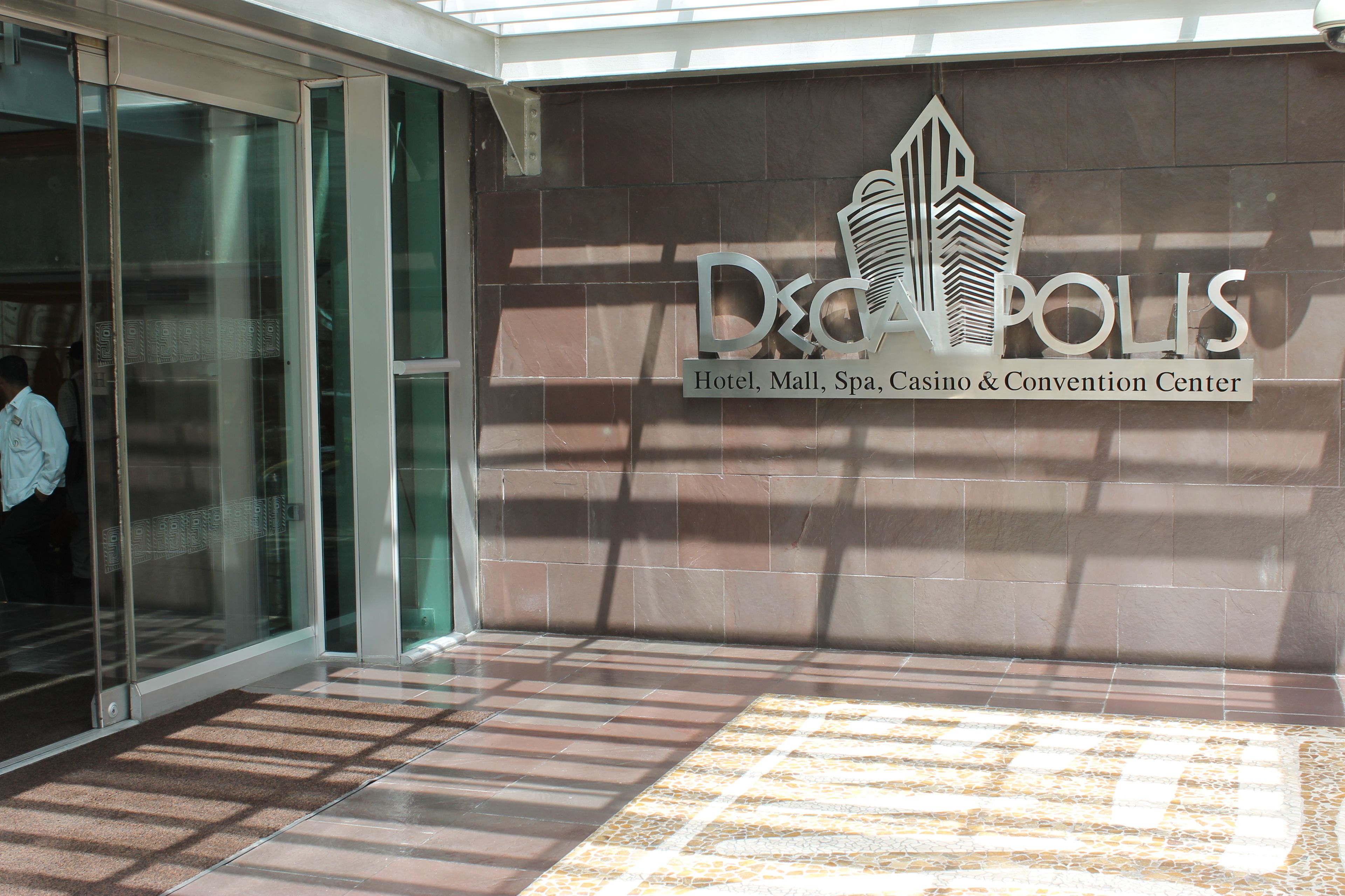 L’entrée d’un immeuble, sur laquelle on peut lire l’inscription : « Hôtel Decapolis, centre commercial, spa, casino et centre de congrès ».