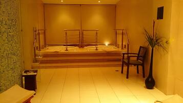 Un cuarto de spa con una bañera grande, una silla y una planta en maceta.
