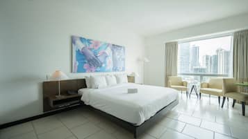 Una habitación de hotel moderna con una cama grande, dos mesitas de noche, un escritorio y una silla.