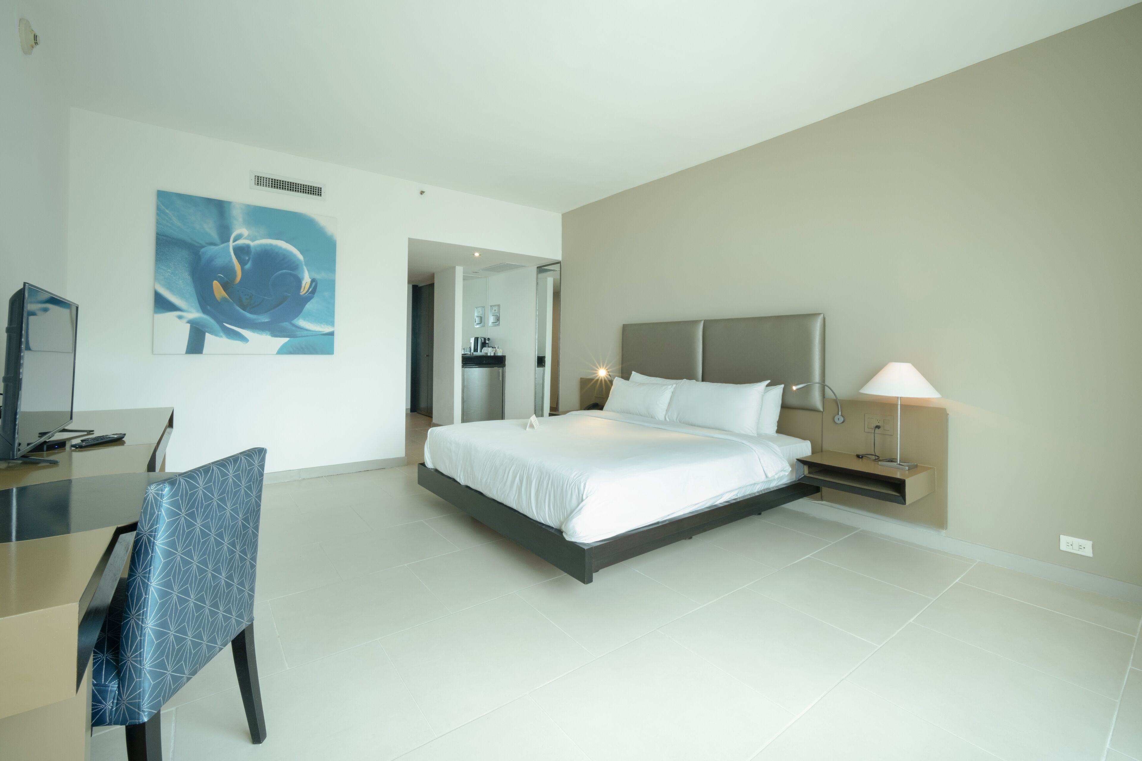 A modern hotel room with a large bed, a desk, and a chair.