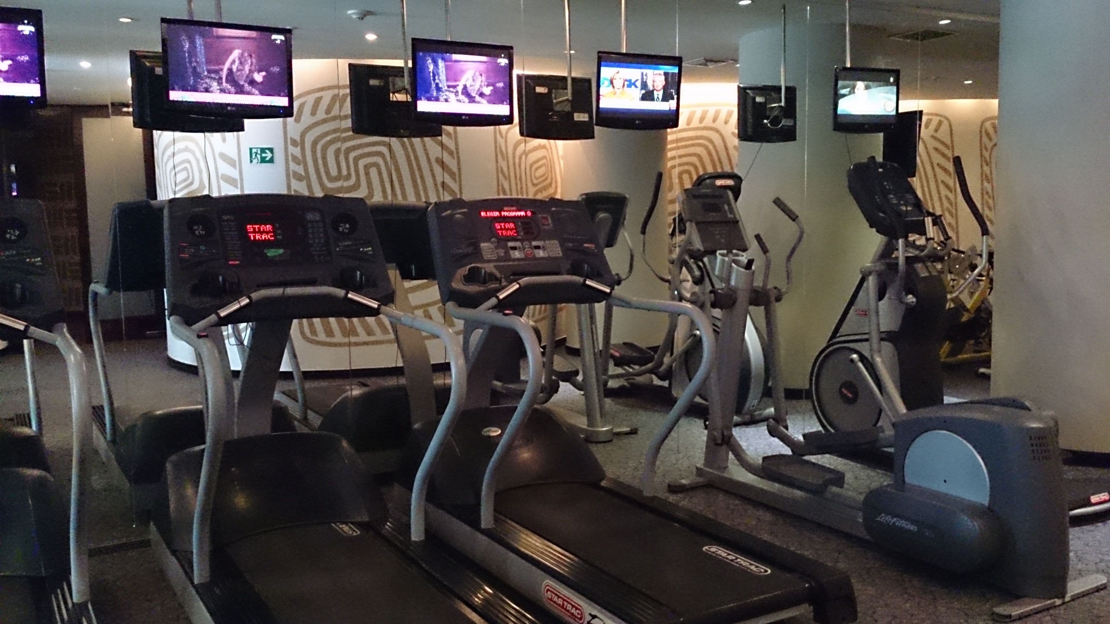 Un gimnasio con cintas de correr, bicicletas estáticas y equipo de ejercicio.