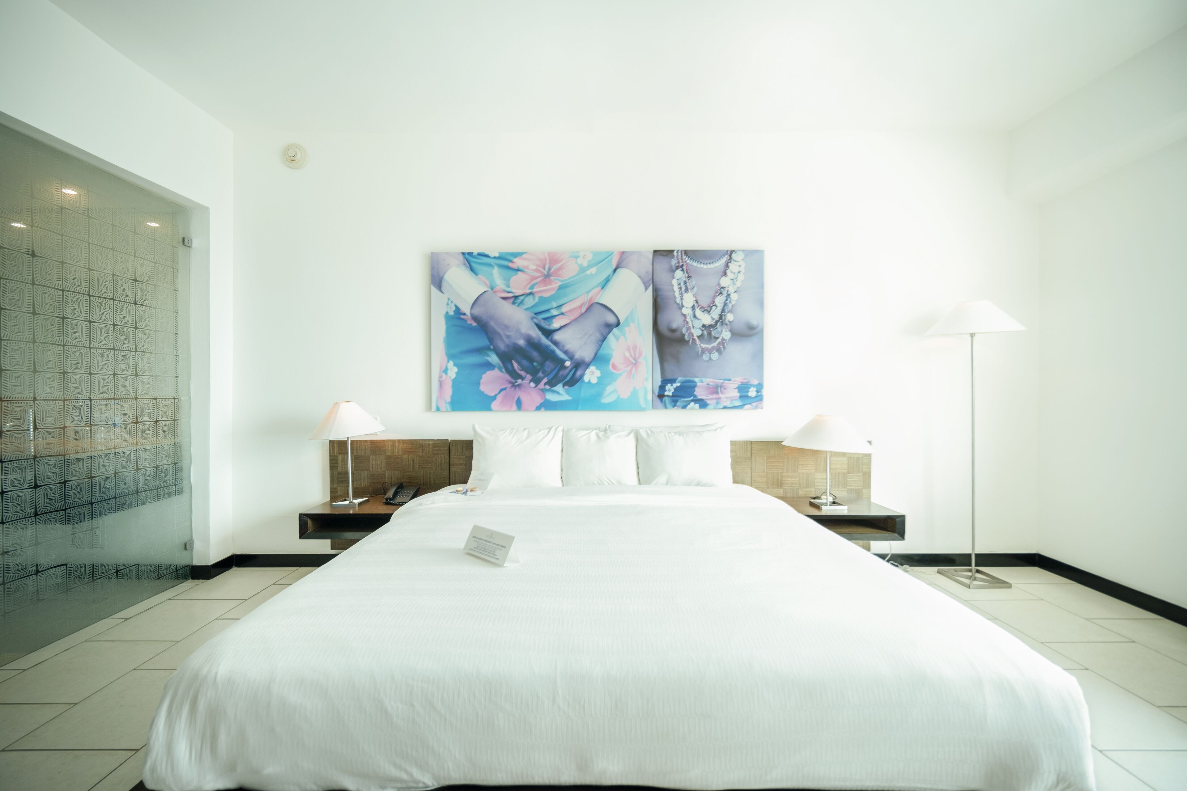 Une chambre d’hôtel avec un grand lit, une douche en verre et une œuvre d’art accrochée au mur.