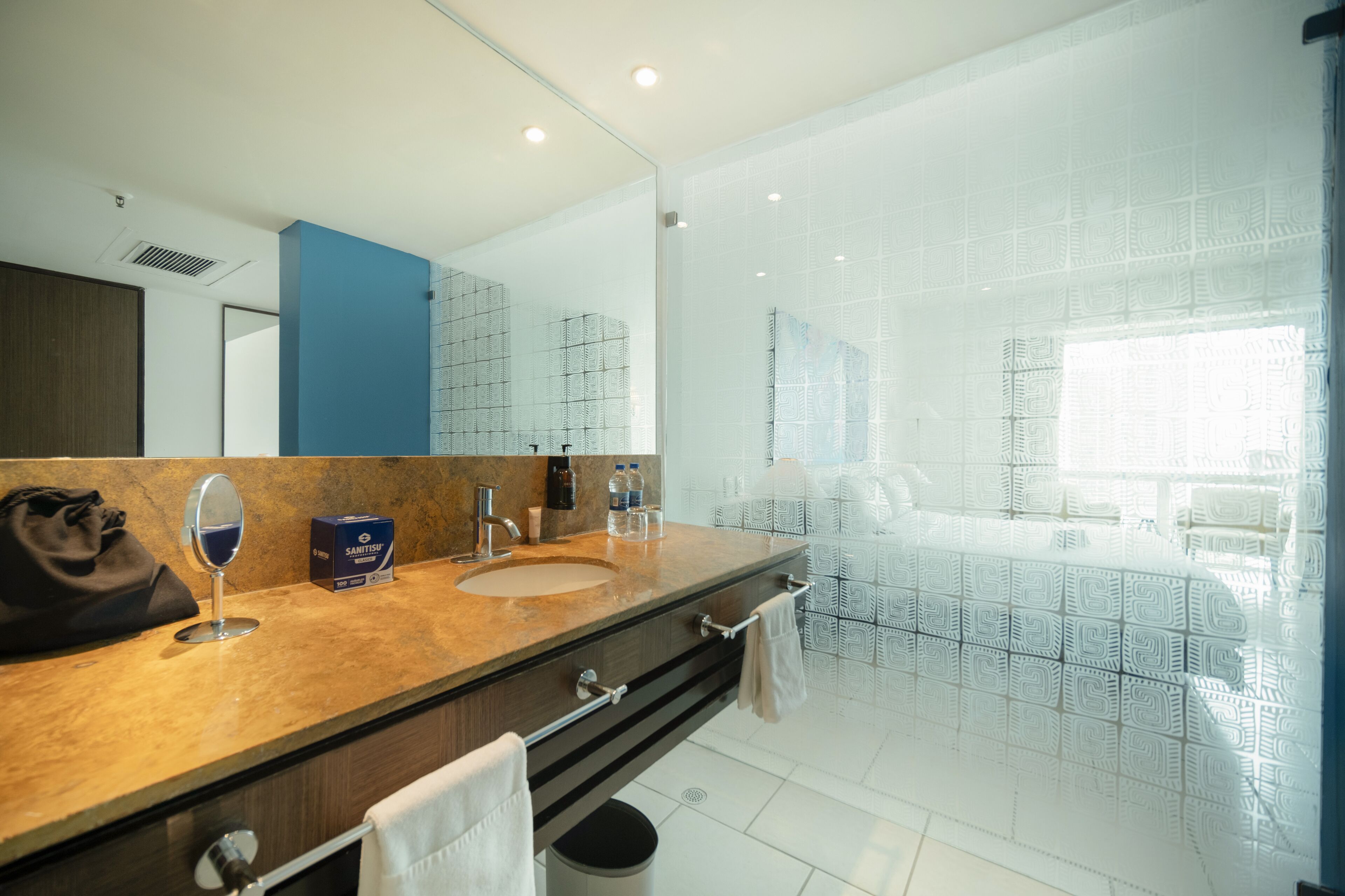 Un baño moderno con un espejo grande, un lavamanos y una zona de ducha.