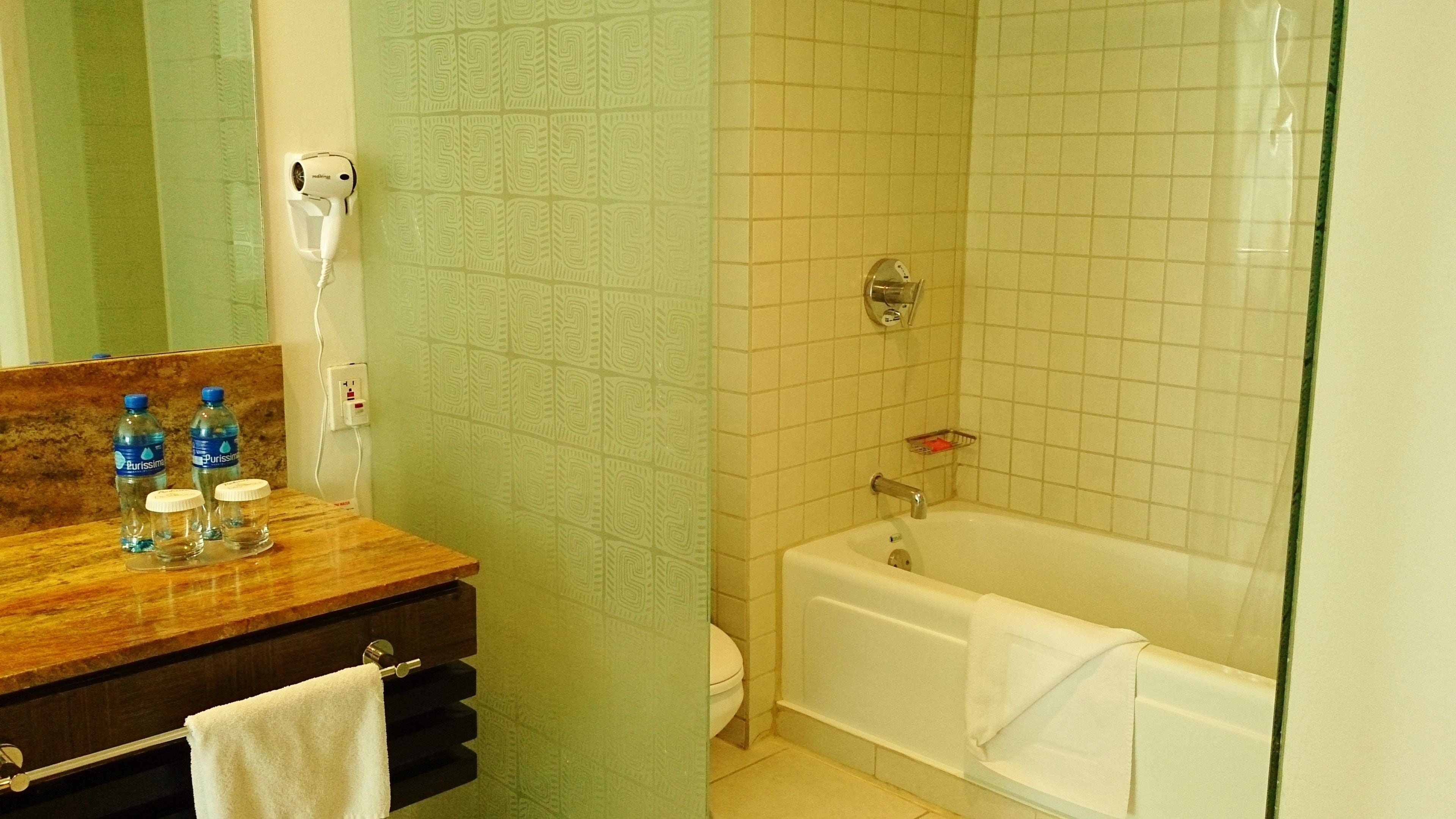 A bathroom with a wooden vanity, a white bathtub, and a mirror.