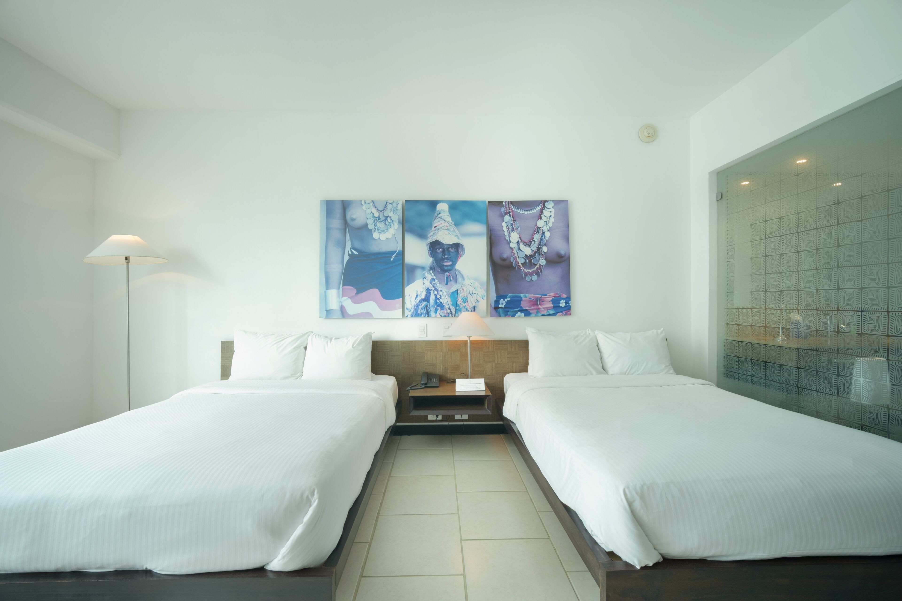 Une chambre d’hôtel avec deux lits, une table de chevet, une lampe et une grande fenêtre donnant sur un beau paysage.