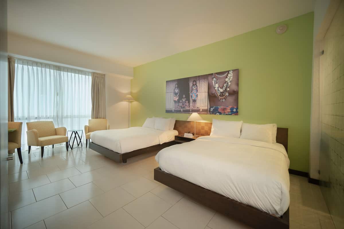 A hotel room with two beds, a sofa, a lamp, and a large painting on the wall.