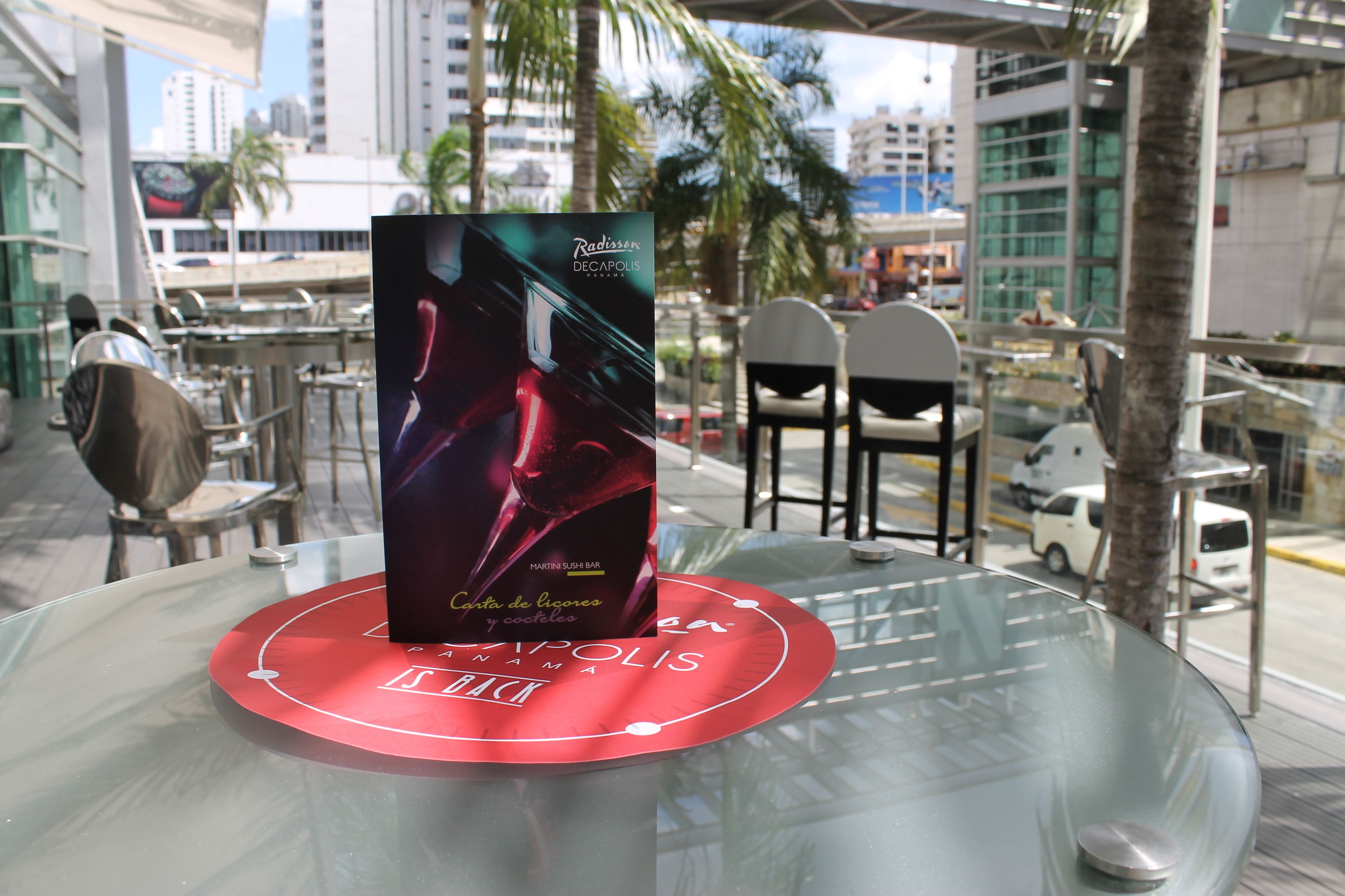 A book titled 'Radisson Decapolis' on a glass table with a red coaster.